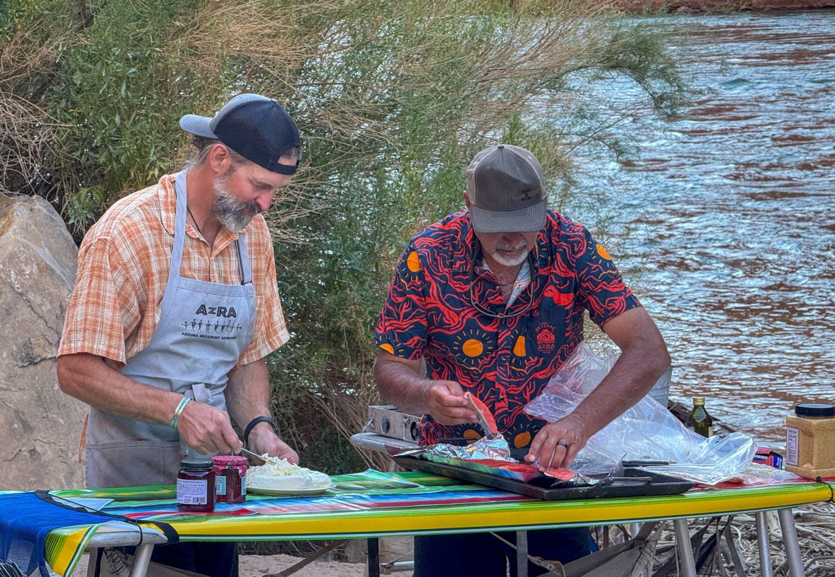 Two men preparing food at a riverside camp beside the Colorado River in the Grand Canyon.